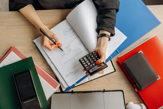 Accountant analyzing financial documents with a calculator on a desk, highlighting business tasks. Selecting accounting tools and suppliers with HMRC, data and exit controls in mind
