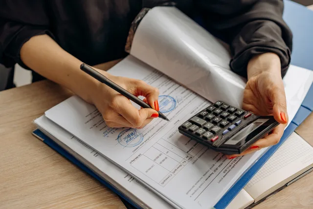 An accountant using a calculator and signing paperwork, showcasing financial analysis. Accounting services outlook: six signals shaping 2027