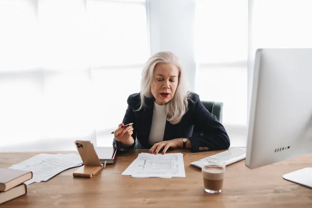 Senior woman in office reviewing financial documents with focused expression. Vendor due diligence for accounting suppliers, from identity and tax links to exit terms